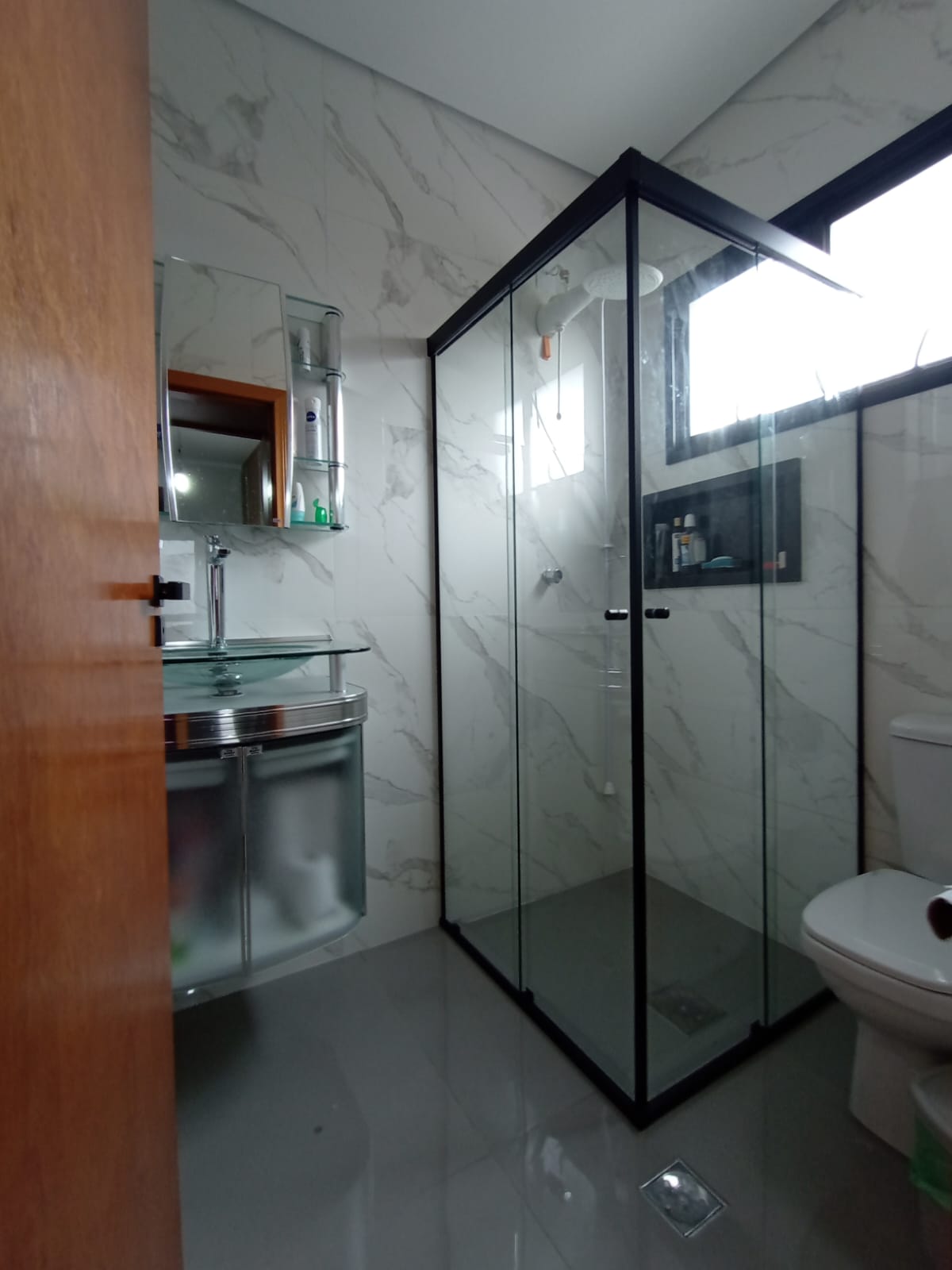 Box de vidro de canto em Valinhos com perfil preto sobre porcelanato marmorizado